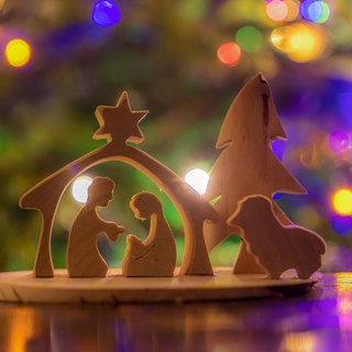 Holzkrippe mit Lichtern im Hintergrund