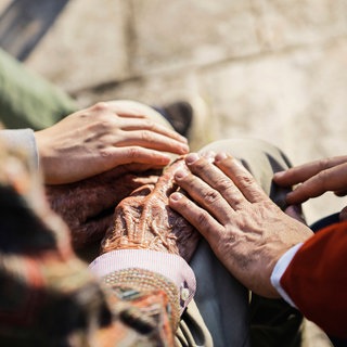 Junge und Vater berühren die Hand eines älteren Mannes.
