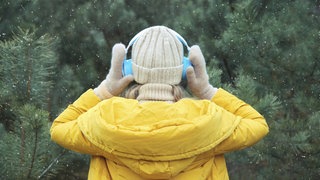 Eine Frau hört draußen Musik mit Kopfhörern