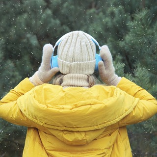 Eine Frau hört draußen Musik mit Kopfhörern