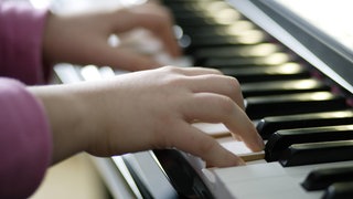 Symbolbild für Musikunterricht: Junge Hände spielen Klavier