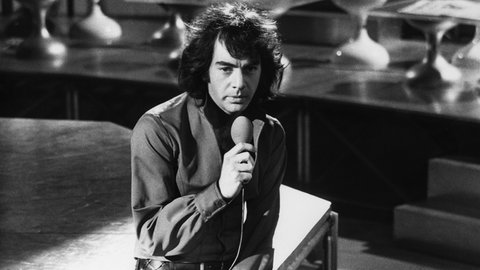 Neil Diamond: Der Musiker und Sänger singt in ein Mikrofon auf einer Bühne.