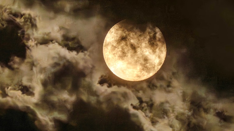 Der Vollmond leuchtet am Nachthimmel, eine Wolke verdunkelt den Mond teilweise