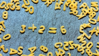 Buchstabennudeln bilden Rechenaufgabe, Mathematik