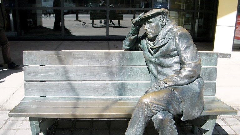 Die lebensgroße Bronzestatue von Glenn Gould, sitzend auf einer Parkbank in der Innenstadt von Toronto, Kanada.