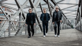 Die drei Bandmitglieder von Frontm3n laufen über eine Brücke