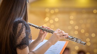 Flötenspielerin beim Üben mit Noten im Konzertsaal