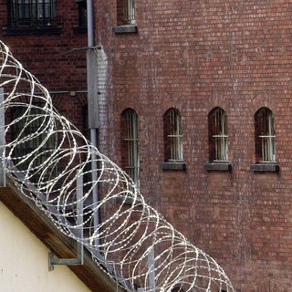 Stacheldraht vor der Fassade einer Justizvollzugsanstalt