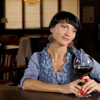 Symbolbild für eine Listening Bar: Eine Frau sitzt mit einem Glas Wein an einer Theke und hört achtsam zu