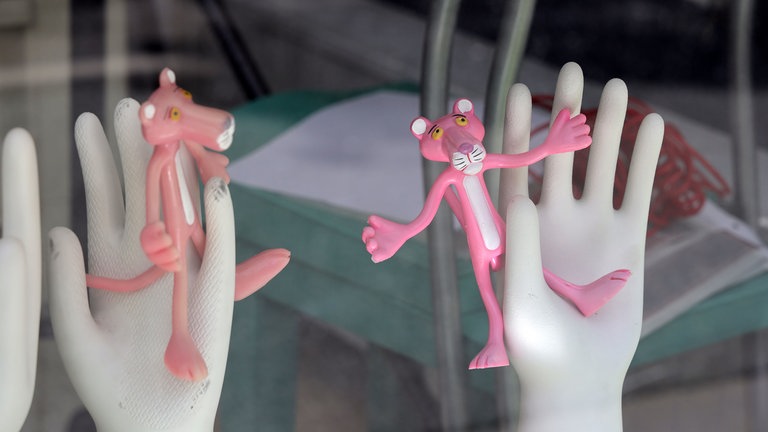 Pink Panther Figuren auf Deko-Händen in einem Schaufenster