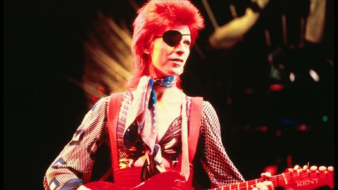 David Bowie mit Augenklappe bei einem Konzert 1970