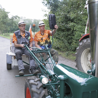 Zwei Männer fahren auf einem Einachser