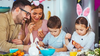 Eine glückliche Familie beim Bemalen von Ostereiern