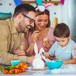 Eine glückliche Familie beim Bemalen von Ostereiern