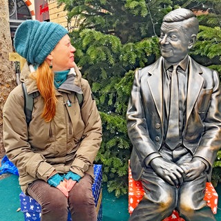 SWR1 Neuanfang: Heike sitzt auf einem Londoner Weihnachtsmarkt neben der metallenen Statue von "Mr. Bean". 