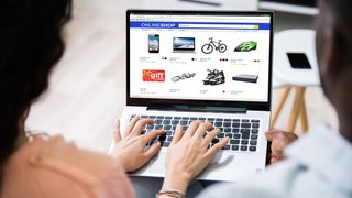 Frau von hinten vor Laptop mit Online-Shop. Wie sicher ist das Bezahlen per Vorkasse?