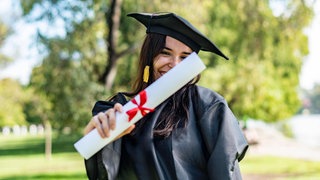 Junge Frau freut sich über die erfolgreiche Promotion - die ist mittlerweile an immer mehr Hochschulen möglich, ohne Kooperation mit einer Universität.