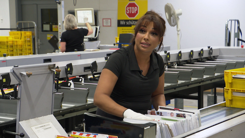 Frau steht an einer Briefsortiermaschine