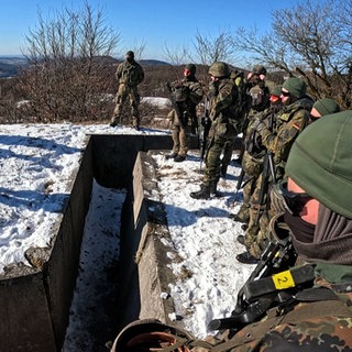 Bei der Spezial-Grundausbildung stehen die angehenden Jäger-Soldaten um einen Graben.