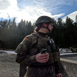 Jäger-Soldatin in Ausbildung trägt Uniform und hält eine Handgranate in der Hand.