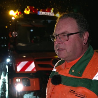 Mitarbeiter der Straßenmeisterei Langenau steht beim Winterdienst frühmorgens vor seinem Einsatzfahrzeug