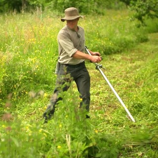 Landschaftspfleger mit der Sense