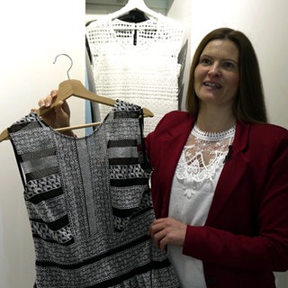 Kathrin Ziebell steht vor einem Kleiderschrank und zeigt eines ihrer Kleider.