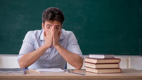 Gestresster Lehrer vor einer Schultafel | Warum viele Lehrkräfte den Beruf wechseln wollen
