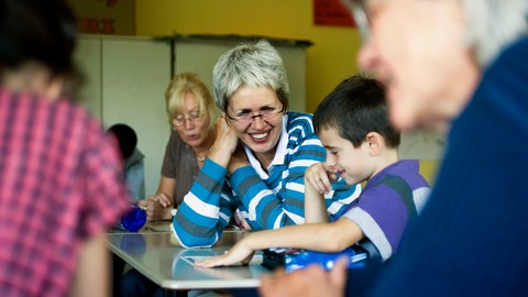 Seniorinnen, die aktiv im Ruhestand sind, helfen Kindern mit dem Lernen in der Schule.