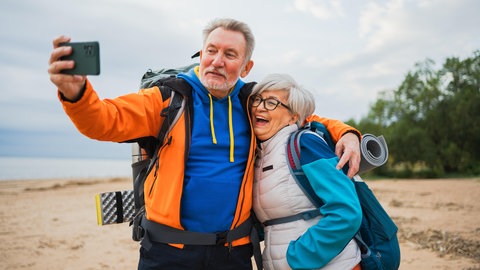 Rentner am Strand machen ein Selfie zusammen.