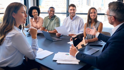Mitarbeiter sitzen für ein Meeting an einem Tisch | Warum Chefs nicht nett, sondern empathisch sein sollten