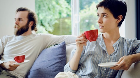 Ein Paar sitzt abgewandt voneinander auf einer Couch. Ein Wendepunkt in einer Beziehung kann das Ende vorhersehbar machen.