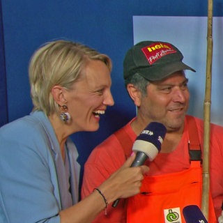 Reporterin Sarah Wilk gut gelaunt mit zwei Straßenreinigern in der Danke-Box