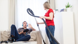 Eine Frau fordert ihren Freund auf im Haushalt zu helfen.