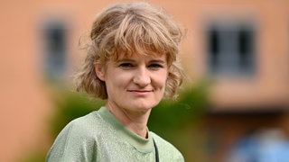 Schauspielerin Eli Wasserscheid steht vor einem Gebäude