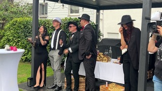 Freundschaftsdinner - 2 Frauen und 3 Männer in abendkleidung stehen in einem Garten