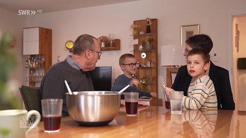 eine Familie sitzt am Tisch