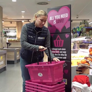 Eine Frau nimmt einen pinken Einkaufskorb