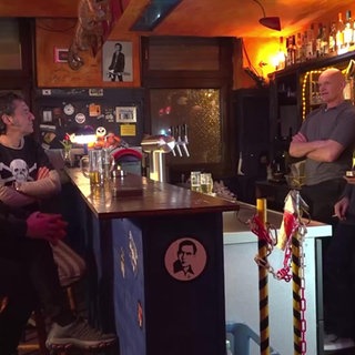 5 Männer sind in einer Kneipe an der Theke zu sehen