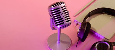 Ein Mikrophon steht auf einem Tisch, daneben liegen Kopfhörer und Notizbuch. Unheilbar erkrankte Mütter und Väter können in einem "Familienhörbuch" eine Audio-Biographie für ihre Kinder erstellen – für die Zeit nach ihrem Tod. Ihre Stimmen und Erinnerungen werden unsterblich.