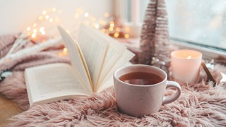 Buch romantisch dekoriert mit Lichterkette, Fell und Tannenbaum
