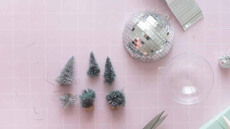 Drei Mini-Tannenbäumchen mit der Schere so kürzen, dass sie gut von innen in die Kugel passen.