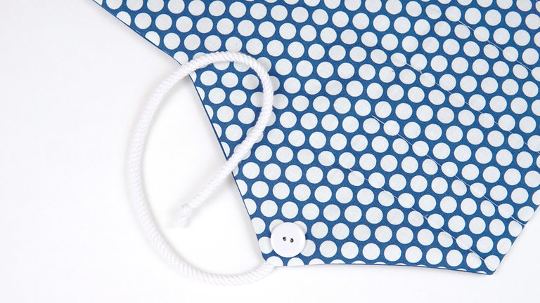 Das Kordelende verknoten und den Knopf markierungsgemäß an der Außenseite der Taschenklappe annähen. 