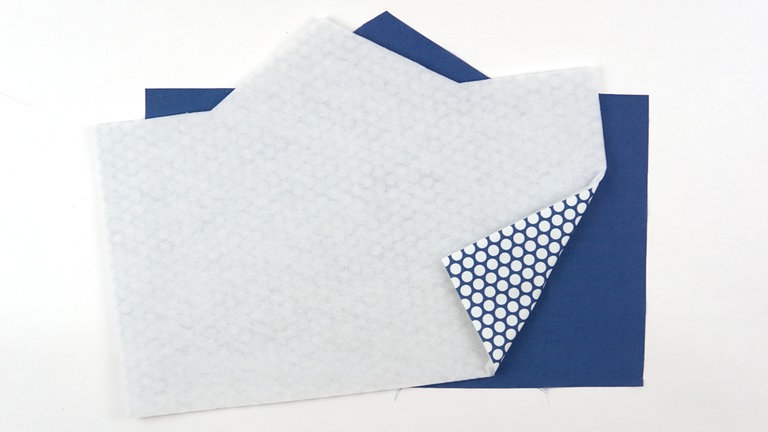 Die Vlieseinlage passgenau auf die linke Stoffseite des Zuschnitts aus dem Außenstoff bügeln.