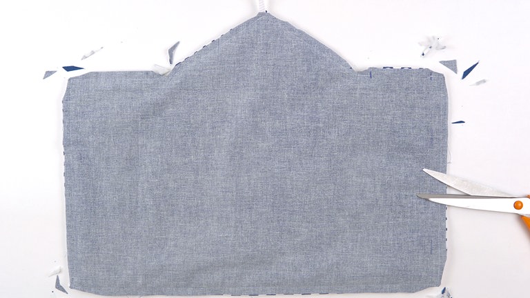 Die Nahtzugaben an den Außenecken schräg zurückschneiden und an den Innenecken v-förmig einschneiden, das Kordelende nicht beschneiden. 