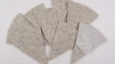 Nach dem Ausschneiden das Vliesofixpapier von den acht Zuschnitten abziehen.