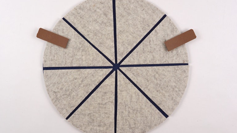 Die Eckstücke mit viel Dampf auf die Grundfläche aufbügeln. Anschließen die zwei Eckstücke markieren, in die später die Lederriemen   Wollfilzstreifen oder Kordelstücke eingenäht werden. Diese zwei Eckstücke im nächsten Schritt noch nicht feststeppen!