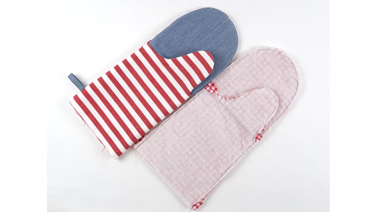 Den Handschuh aus Futterstoff links auf links in den Handschuh aus Oberstoff schieben und an der Eingriffkante aufeinanderheften. Knappkantig mit langem Geradstich zusammennähen.