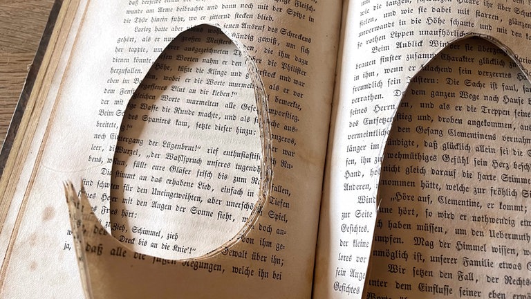 Auf eine Buchseite von Hand ein Ei zeichnen. Es sollte etwas kleiner sein als das Ei aus Draht. Das Ei mehrlagig ausschneiden. 