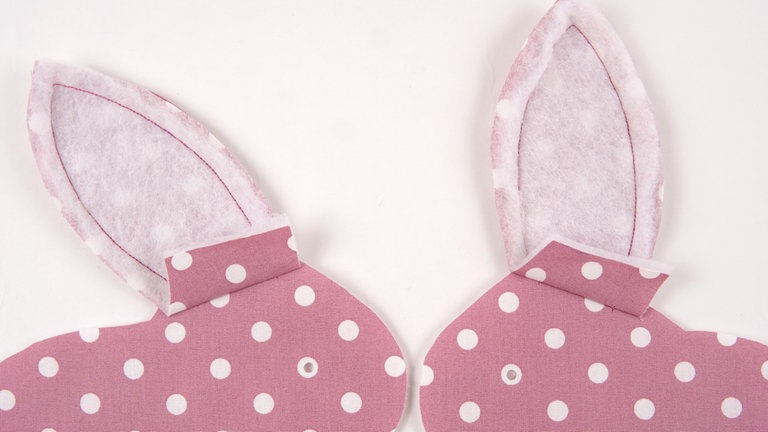 Die Nahtzugaben an den Unterkanten der Ohren nach oben bügeln. 